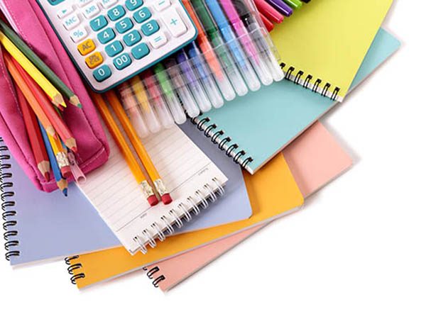 Various school supplies including notebooks, calculator and pink pencil case isolated against a white background